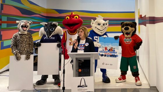 Citizens for Modern Transit Executive Director Kim Cella speaks at a kickoff event for the College Transit Challenge while surrounded by mascots from participating schools St. Louis Community College, Southwestern Illinois College, the University of Missouri–St. Louis, Saint Louis University and the Washington University in St. Louis