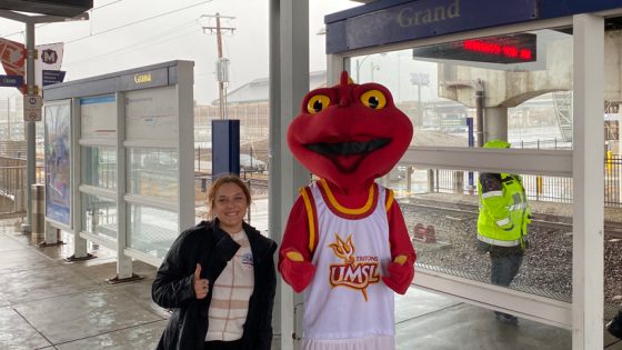 Graduate student Taylor Cook and Louis the Triton stand on the platform at the Grand MetroLink station