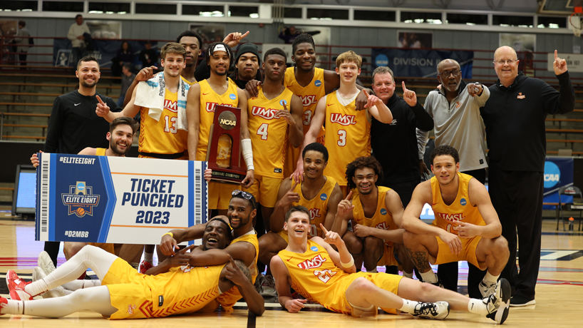 Members of the UMSL men's basketball team pose with their regional championship trophy and a sign that says "Ticket Punched 2023"