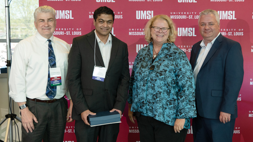 Chris Spilling, Vijay Anand, Kristin Sobolik and Steven Berberich pose in front of an UMSL backdrop at the Research and Innovation Reception