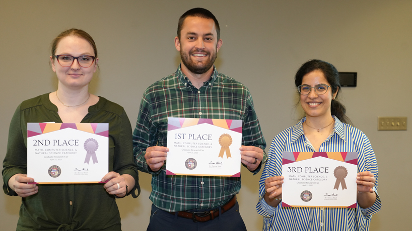 Oana Coman, George Todd and Palak Sondhi hold up their certificates for placing in the top three in the Graduate Research Fair's Math, Computer Science and Natural Sciences category