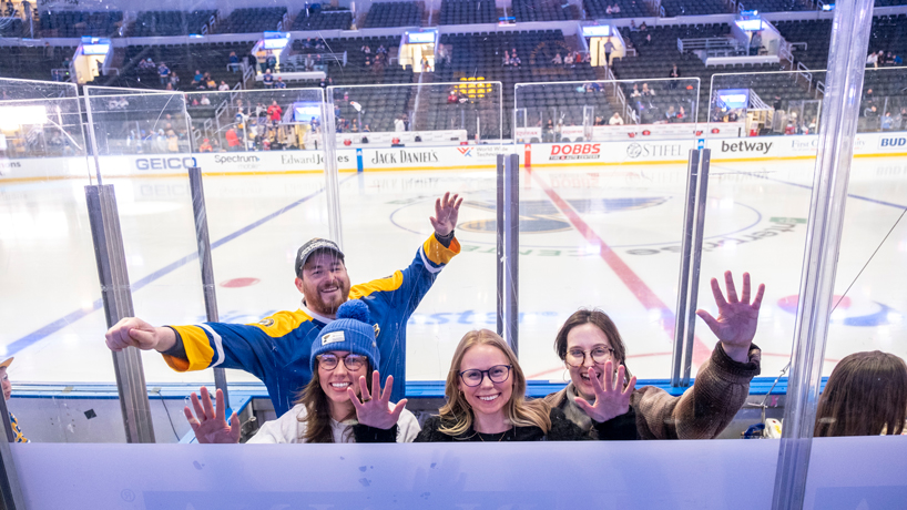 Friends (from left) Bobby Castille, Beth Kernaghan, Adrienne Groves and Claire Teichman tap the glass from inside the penalty box during "UMSL Night at the Blues"