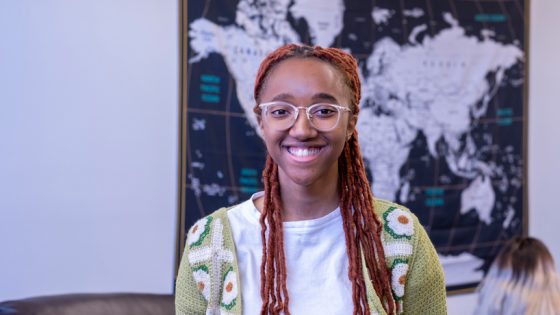Student Georgeann McLemore stands in front of a map in the UMSL Global office