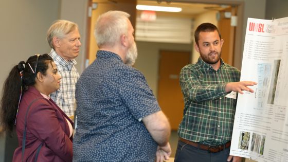 Biology student George Todd points to something on his poster display as he talks to faculty members and another graduate student about his research during the annual Graduate Research Fair in the MSC