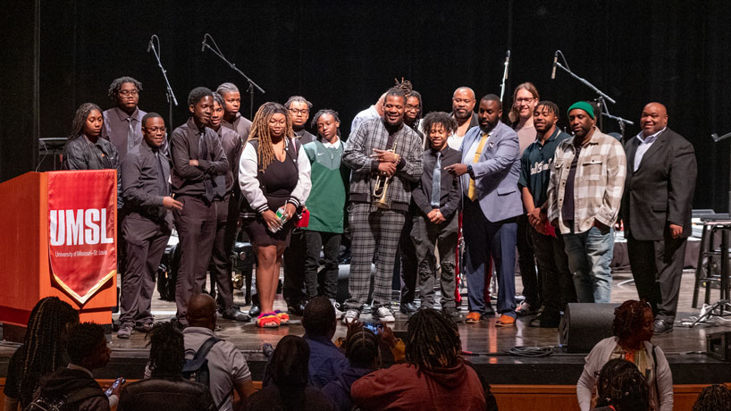 Keyon Harrold stands with students after his talk on jazz history.