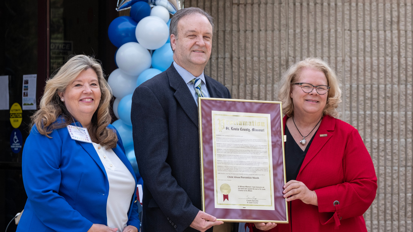 St. Louis County Executive Dr. Sam Page presents a resolution to Jerry Dunn and Chancellor Kristin Sobolik during an event commemorating Child Abuse Prevention Month