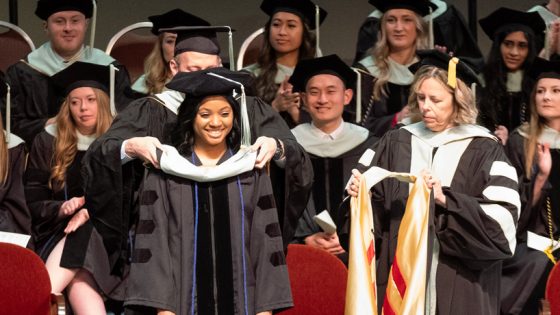 College of Optometry graduate Gabriella Watson, Black woman in black cap and gown, receives her doctoral hood