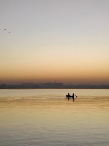 a silhouette of a lone boat on a lake with dusky sky in the background