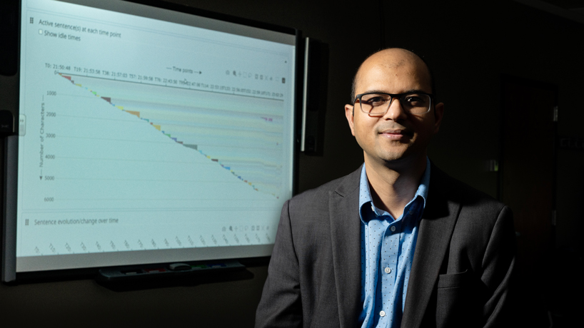 Computer Science Assistant Professor Badri Adhikari sitting in front of a screen displaying a graph produced by the online learning tool Process Feedback that he developed