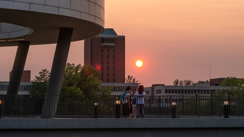 A family pauses to take in the sunset on the walkway outside of the Recreation and Wellness Center