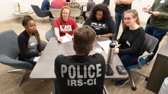 UMSL students Desiree Brooks, Angela Truesdale, Jarchelle Williams and Dora Bell sit around a table interviewing an IRS Criminal Investigation special agent