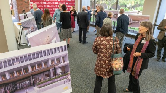 Attendees of the library renovation kickoff celebration mingle and look at renderings of the planned renovation