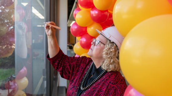 Chancellor Kristin Sobolik writes on the glass where the new north entrance to University Libraries will be built
