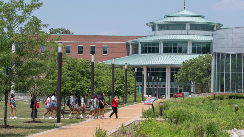 A student tour guide leads a group of prospective students on a tour past the Millennium Student Center