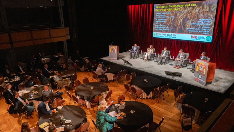 Panelists sit on stage while the audience sits at attention during the Geography 2050 STL: Feeding Our Future Planet symposium inside the Lee Theater