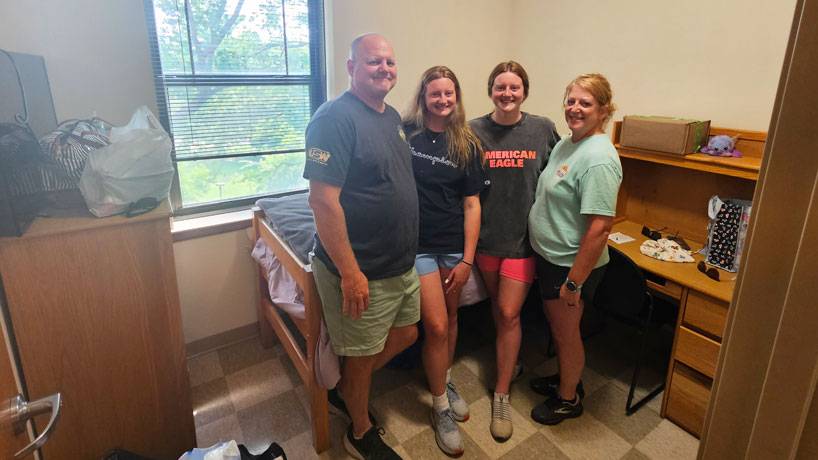 Audrey and Ella Lantz stand with their parents in a room in Oak Hall