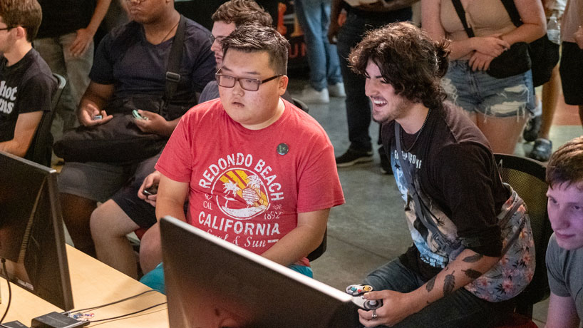 Joseph Lee, Asian man in red shirt, concentrates during a Super Smash Bros. Ultimate match