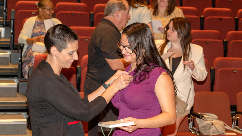 University of Missouri–St. Louis College of Nursing alumna Abigail Fitzhugh attaches an UMSL legacy pin to her freshman daughter Eliana Fitzhugh