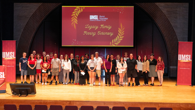 New UMSL students stand on stage with their alumni parents during the Legacy Family Pinning Ceremony