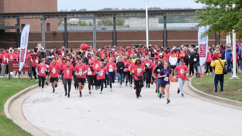 Runners break from the starting line at the beginning of the UMSL Alumni Association 5K Run/Walk