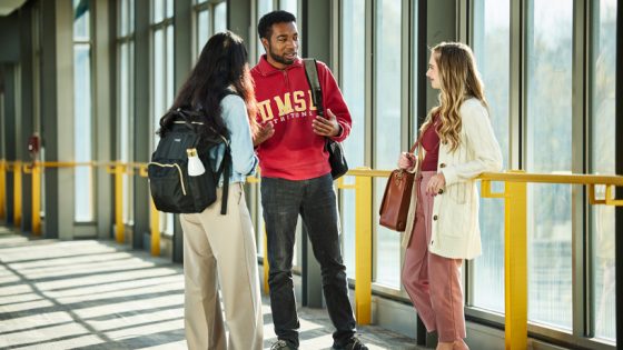 Three students converse on the Millennium Student Center bridge