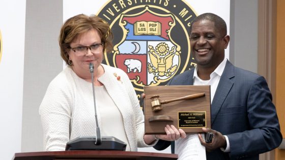 Chair-elect Robin Wenneker presents a plaque to outgoing board chair Michael Williams during Thursday's meeting