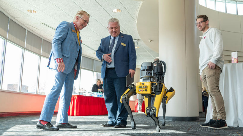 Provost Steven J. Berberich (center) talks to Curator Robert Fry about Spot, UMSL's agile robot dog, during a break in the board of curators meeting