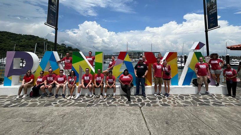 UMSL Online MBA students sit in front of a large Panama sign