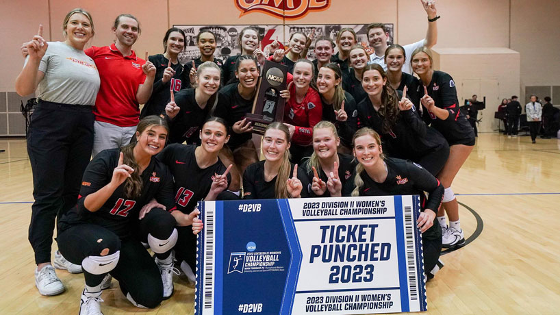 The UMSL volleyball team gathers for a team photo with the Ticket Punched sign after winning the NCAA Division II Midwest Region title and booking a spot in the national quarterfinals