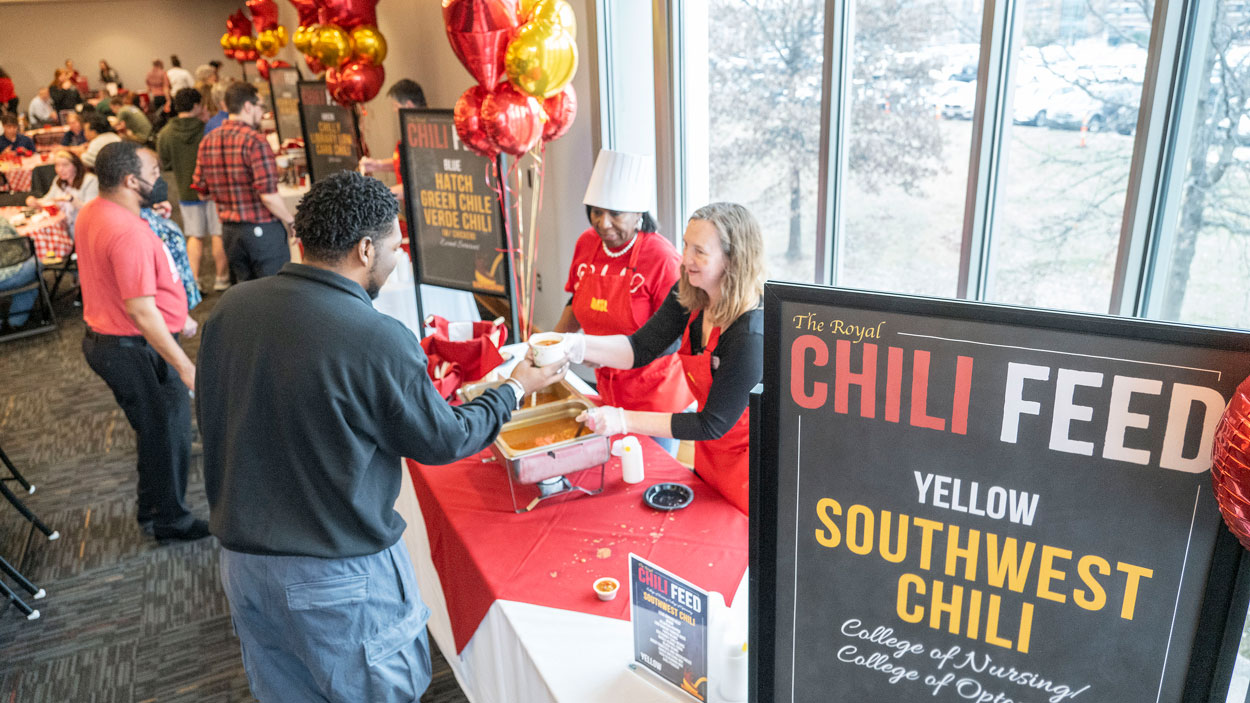 Senior business administration major Jalen Walker-Wright gets a cup of southwest chili from Vanessa Loyd, a teaching professor in the College of Nursing, and Erin Schaeffer, senior educational program coordinator in the College of Optometry, during the homecoming Chili Feed at the University of Missouri–St. Louis.