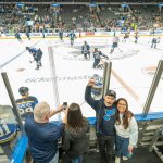 Student recruitment specialist Sean Marshall lets out a cheer as he stands in the penalty box taking pictures before the start of the St. Louis Blues game last Tuesday against the Colorado Avalanche