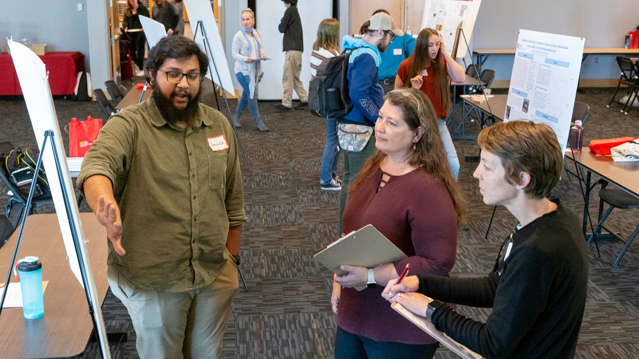 Biology PhD student Danish Gul discusses his research with faculty members Wendy Olivas and Meghann Humphries during the annual Graduate Research Fair on April 19. 