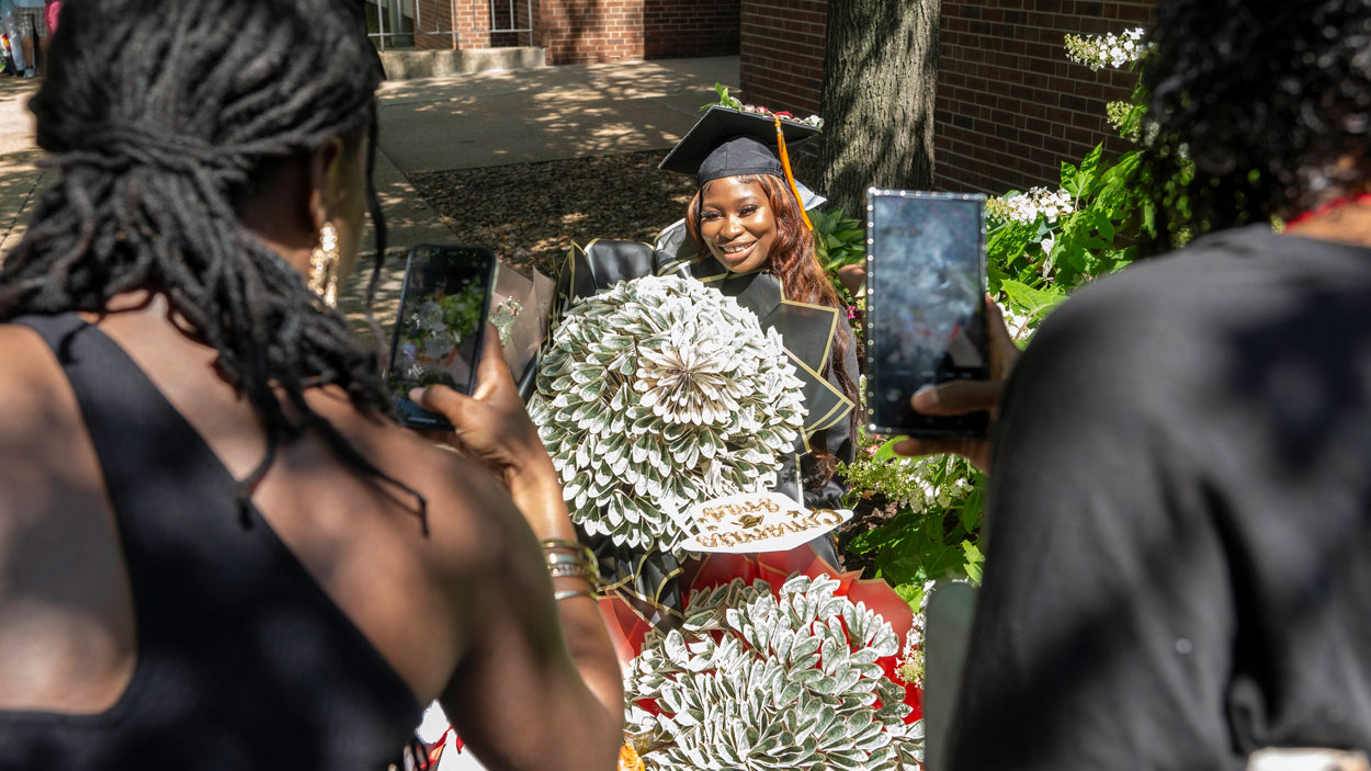 Nursing graduate Beauty Tinyan poses for photos outside with bouquets of money she received from her family
