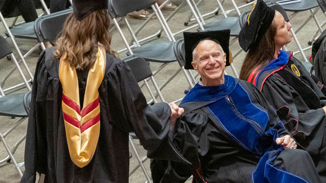 Accounting Professor Steve Moehrle fist bumps a graduate of the College of Business Administration after she leaves the stage.