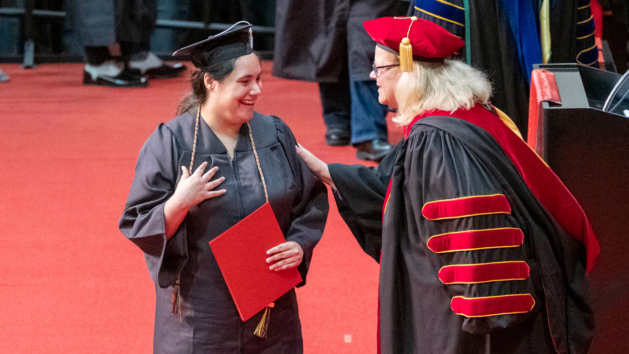 Music graduate Rachel Anthonis, who sang the national anthem at Saturday morning's ceremony, receives congratulations from Chancellor Sobolik as she walks across the stage.