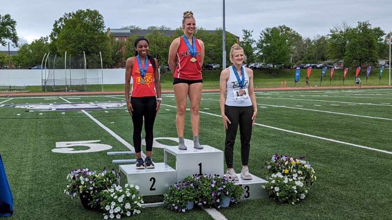 UMSL athlete Kennedy Moore stands on the second-place podium at the GLVC Outdoor Track and Field Championships