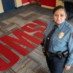 New UMSL Chief of Police Marisa Smith stands in the lobby of the UMSL Police Department with "UMSL" on the carpet