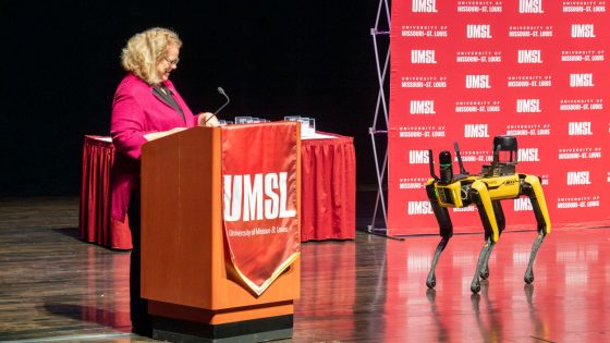 Spot, the agile mobile robot dog, standing on stage near Chancellor Kristin Sobolik at the Blanche M. Touhill Performing Arts Center