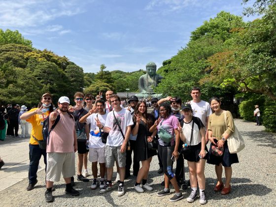 students pose in front of the giant Buddha statue in Kamakura