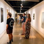 University of Missouri–St. Louis students take in the fall exhibition "Turn Upon Them: Reveal to Heal" during the opening reception hosted by Gallery 210@FAB on Aug. 29