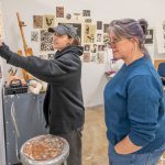 Visiting artist Amy Callner (right) listens as Maria Corrao, a senior fine arts major, talks about her collages and printmaking projects.