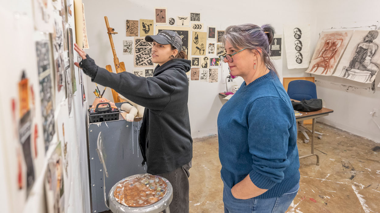 Visiting artist Amy Callner (right) listens as Maria Corrao, a senior fine arts major, talks about her collages and printmaking projects.