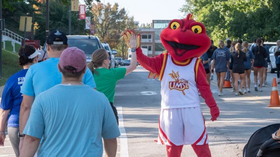 Louie the Triton high fives participants in the UMSL Alumni 5K as they walk up West Drive