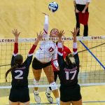 Hannah Copeland rises to hit a ball as two defenders jump at the net to try to block her