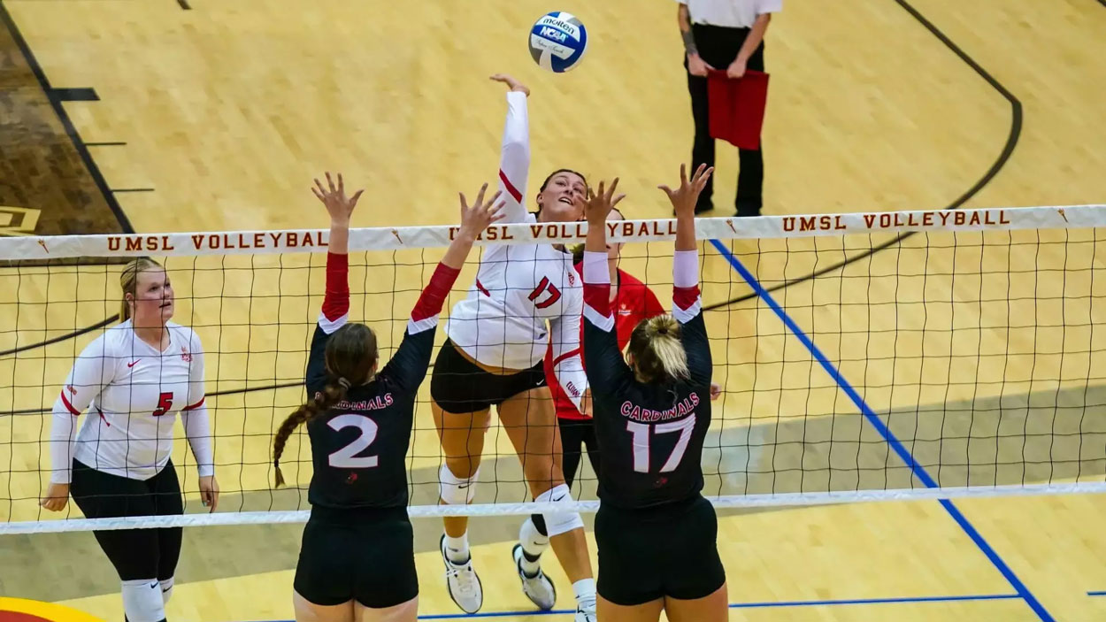 Hannah Copeland rises to hit a ball as two defenders jump at the net to try to block her