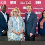 UMSL Vice Chancellor Reggie Hill, Chancellor Kristin Sobolik, Greater St. Louis Area Council Scouting CEO Joe Sadewasser and Director of Human Resources Ronda Smith stand in front of an UMSL backdrop after finalizing a new partnership agreement at a signing ceremony