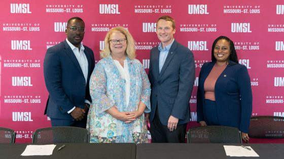 UMSL Vice Chancellor Reggie Hill, Chancellor Kristin Sobolik, Greater St. Louis Area Council Scouting CEO Joe Sadewasser and Director of Human Resources Ronda Smith stand in front of an UMSL backdrop after finalizing a new partnership agreement at a signing ceremony