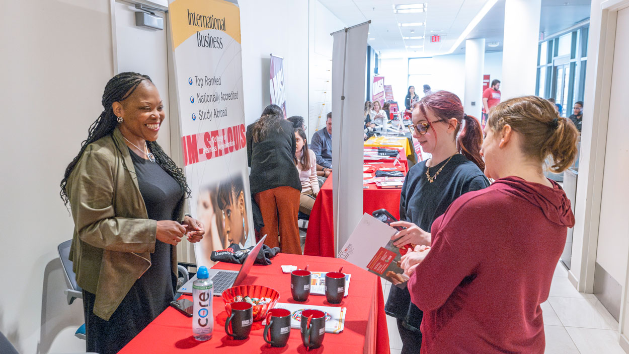 Renita Miller, the program manager for the University of Missouri–St. Louis International Business Institute, speaks with students Lexe Sullivan and Nicole White Campbell during the College of Business Administration's Majors/ Minors Fair last Thursday on the first floor of Anheuser-Busch Hall