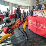 UMSL's newly renamed agile mobile robotic dog, Titan, visits the UMSL Graduate Business table and meets a few smiling faces at last week's Spring Involvement Jamboree in the Millennium Student Center as it showed off its new look