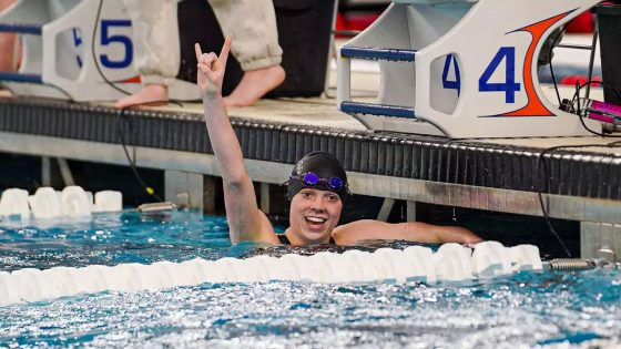 UMSL swimmer Justice Beard hold up her arm in celebration after winning the women's 500-yard freestyle race
